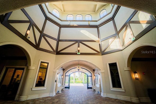 corridor with a high ceiling, baseboards, a chandelier, and arched walkways