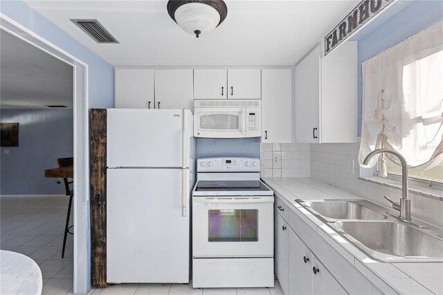1802 Robinhood St, Sarasota, FL 34231 - kitchen with visible vents, a sink, light tile patterned floors, white appliances, and white cabinetry