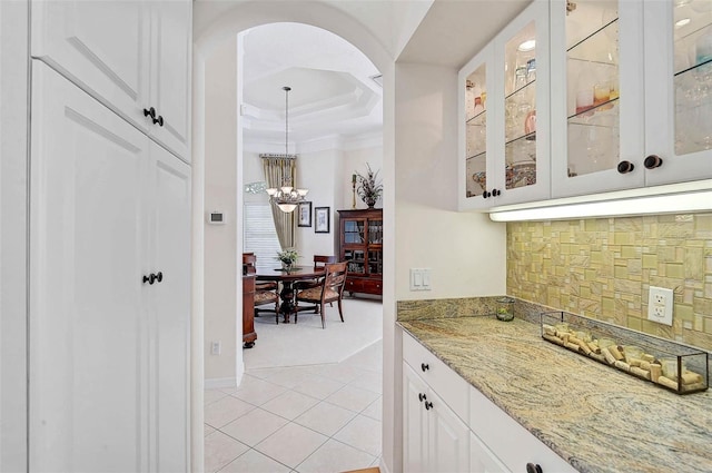 2111 Muskogee Trl, Nokomis, FL 34275 - bar with crown molding, light tile patterned flooring, a tray ceiling, arched walkways, and backsplash