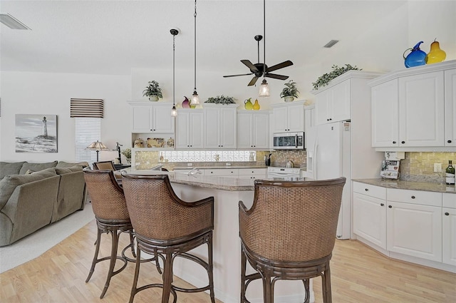 2111 Muskogee Trl, Nokomis, FL 34275 - kitchen with ceiling fan, range with electric stovetop, visible vents, stainless steel microwave, and light wood finished floors