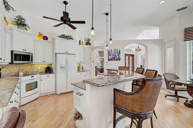 2111 Muskogee Trl, Nokomis, FL 34275 - kitchen featuring visible vents, white appliances, ceiling fan, tasteful backsplash, and arched walkways