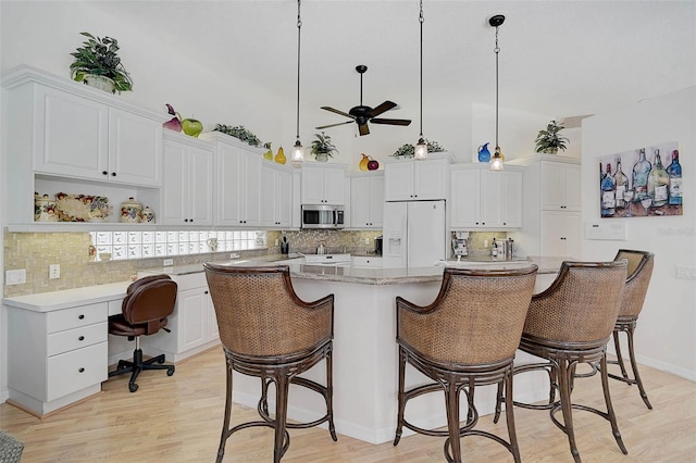 2111 Muskogee Trl, Nokomis, FL 34275 - kitchen with white cabinets, a ceiling fan, stainless steel microwave, and white refrigerator with ice dispenser