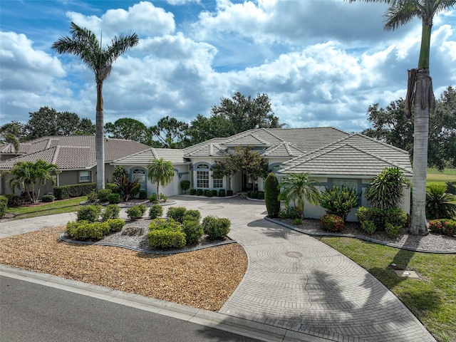 2111 Muskogee Trl, Nokomis, FL 34275 - view of front of house featuring curved driveway, a garage, stucco siding, and a tiled roof