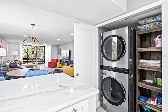 clothes washing area with recessed lighting, laundry area, stacked washer / drying machine, and a notable chandelier