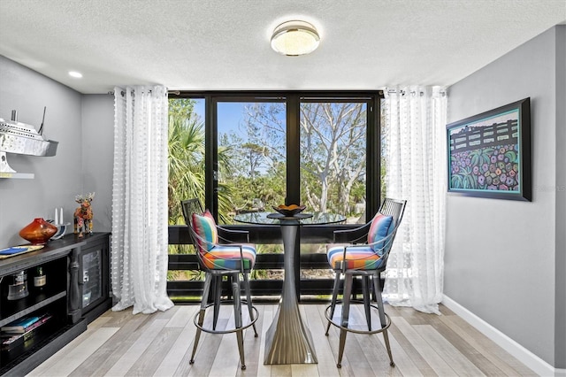 dining room with a textured ceiling, baseboards, and wood finished floors