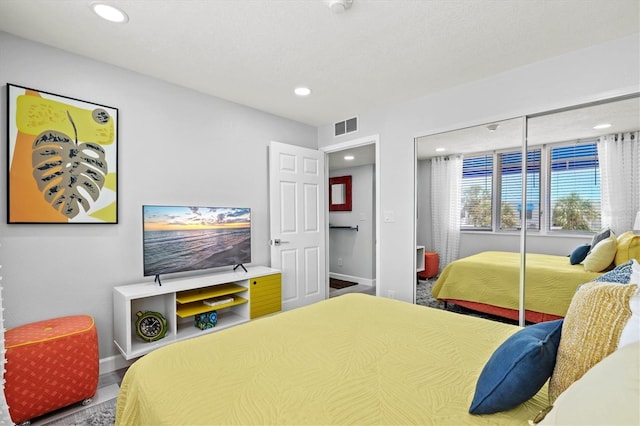bedroom featuring wood finished floors, a closet, visible vents, baseboards, and recessed lighting