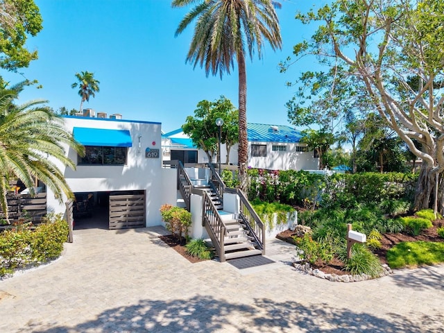 view of front of house with stairs, stucco siding, and decorative driveway