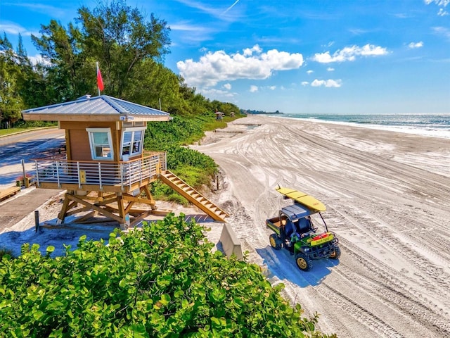 view of home's community featuring stairs, a water view, and a beach view