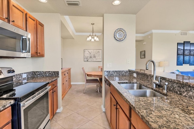 kitchen featuring brown cabinets, a sink, stainless steel appliances, a notable chandelier, and visible vents