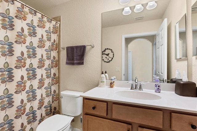 full bath featuring toilet, visible vents, a shower with shower curtain, vanity, and a textured wall