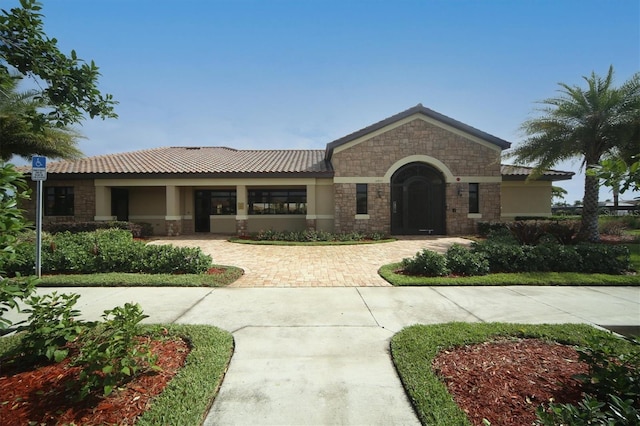 view of front of property with stone siding, stucco siding, and a tile roof