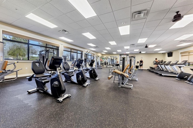 exercise room with baseboards, visible vents, and a drop ceiling