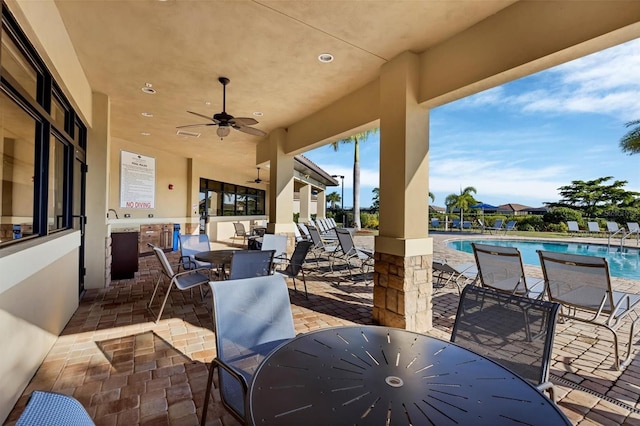 view of patio featuring outdoor dining area, a ceiling fan, and a community pool