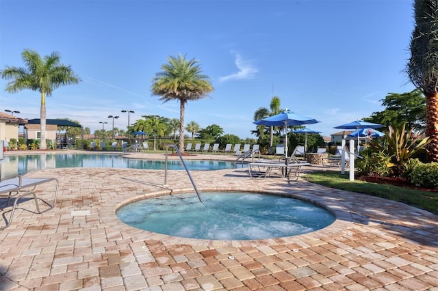 pool with a patio area and a community hot tub