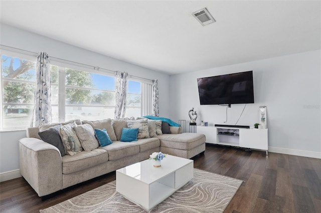 living room featuring visible vents, dark wood-style flooring, and baseboards