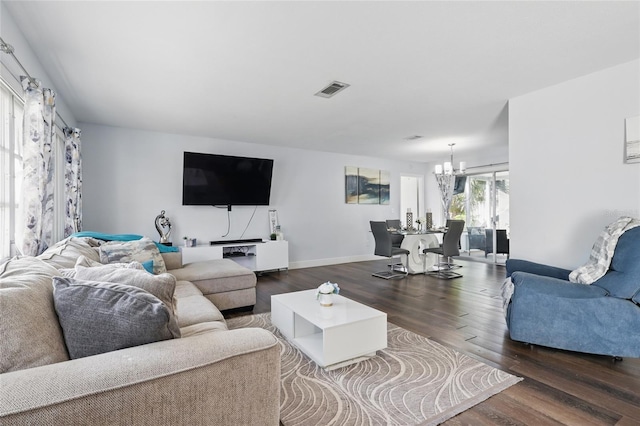 living room with baseboards, visible vents, wood finished floors, and a notable chandelier