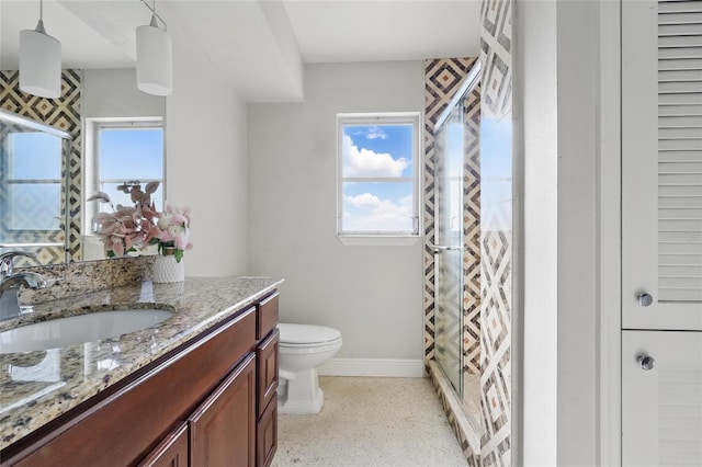 full bath featuring a shower stall, speckled floor, vanity, baseboards, and toilet
