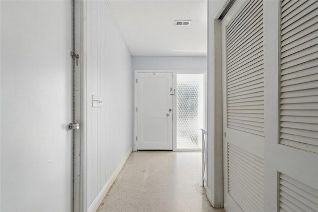 hallway featuring baseboards, visible vents, and light speckled floor