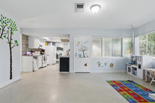 recreation room with light speckled floor, baseboards, and visible vents