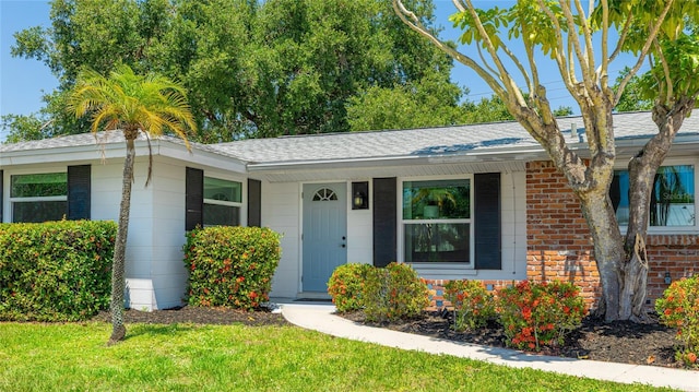 6529 Seagate Ave, Sarasota, FL 34231 - ranch-style home with brick siding, roof with shingles, and a front yard
