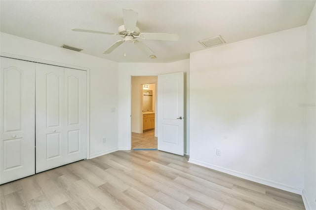 unfurnished bedroom with baseboards, a closet, light wood-style flooring, and visible vents