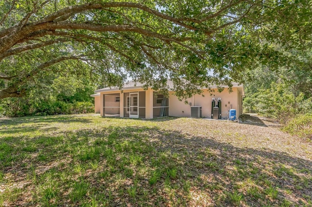 back of house with a yard, central AC, a sunroom, and stucco siding