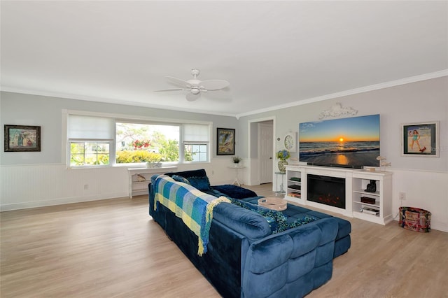 1722 Hazelwood St, Sarasota, FL 34231 - living room featuring crown molding, light wood-type flooring, ceiling fan, wainscoting, and a glass covered fireplace