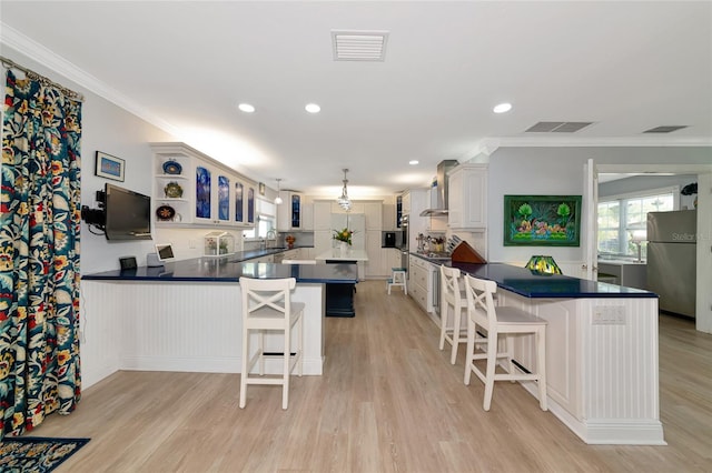 1722 Hazelwood St, Sarasota, FL 34231 - kitchen featuring freestanding refrigerator, a peninsula, dark countertops, crown molding, and wall chimney exhaust hood