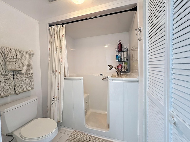 full bathroom with toilet, curtained shower, and tile patterned flooring