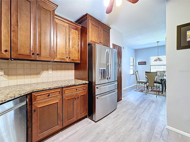 kitchen with stainless steel appliances, a textured ceiling, decorative backsplash, and light stone counters