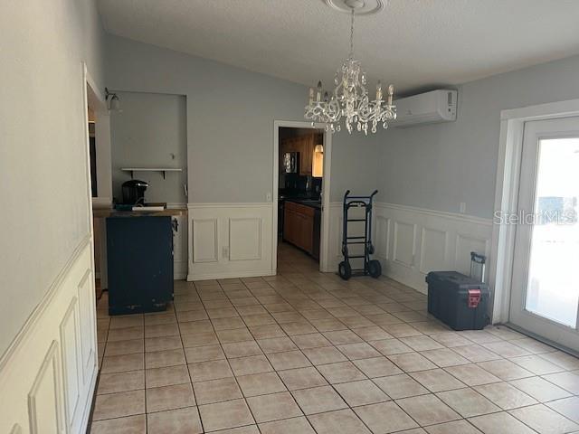 6383 N Jade Ter, Crystal River, FL 34428 - dining room with an AC wall unit, an inviting chandelier, light tile patterned flooring, and a wainscoted wall