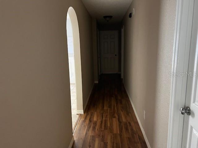 6383 N Jade Ter, Crystal River, FL 34428 - hall featuring arched walkways, baseboards, and dark wood finished floors