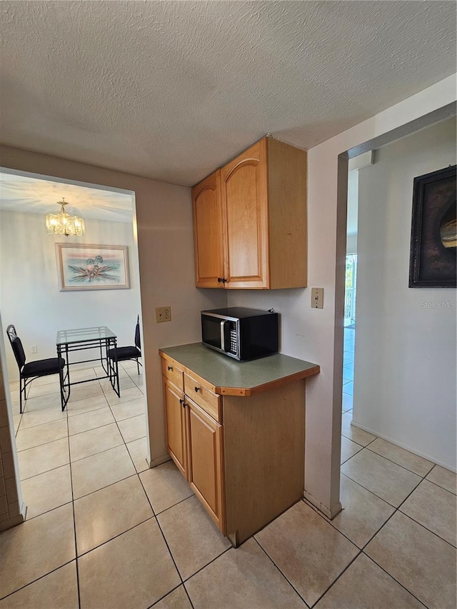 2321 Canal Dr Unit F25, Bradenton, FL 34207 - kitchen with stainless steel microwave, light tile patterned floors, a textured ceiling, and a chandelier