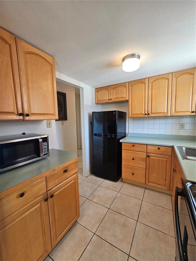 2321 Canal Dr Unit F25, Bradenton, FL 34207 - kitchen with black appliances, light tile patterned floors, a textured ceiling, and tasteful backsplash