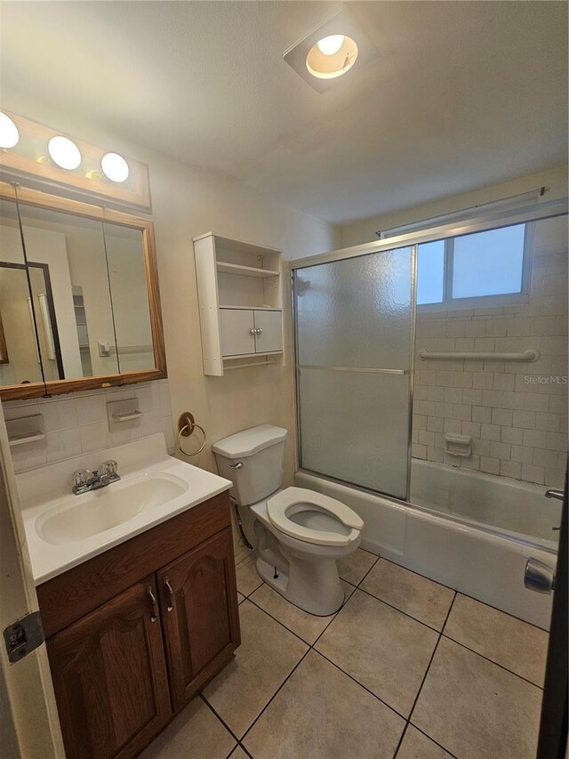 2321 Canal Dr Unit F25, Bradenton, FL 34207 - bathroom featuring vanity, toilet, tile patterned flooring, combined bath / shower with glass door, and tasteful backsplash