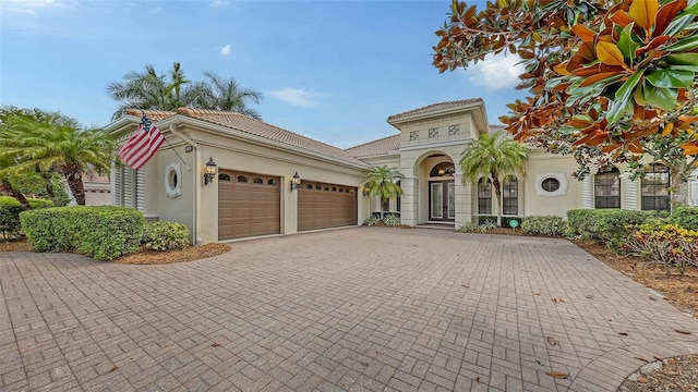 6919 Dominion Ln, Lakewood Ranch, FL 34202 - mediterranean / spanish-style house with an attached garage, stucco siding, decorative driveway, and a tiled roof