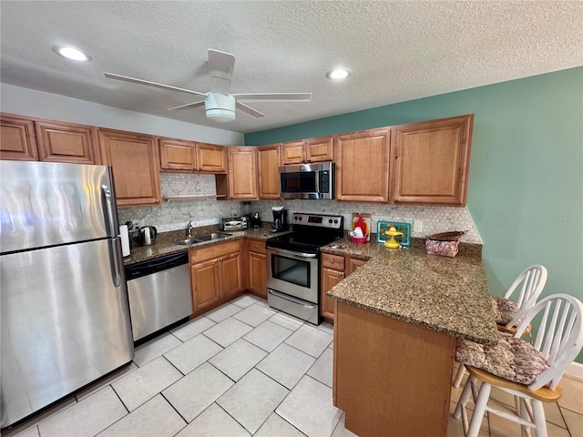 kitchen featuring open shelves, a peninsula, a sink, appliances with stainless steel finishes, and backsplash