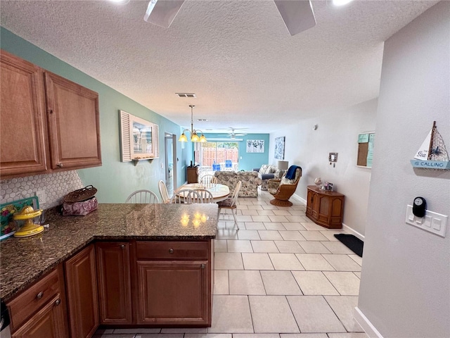 kitchen featuring visible vents, decorative backsplash, a peninsula, light tile patterned flooring, and baseboards