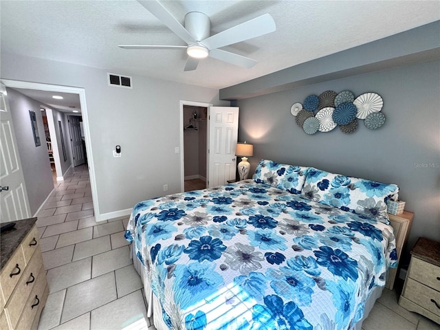 bedroom with a ceiling fan, a textured ceiling, visible vents, light tile patterned floors, and baseboards