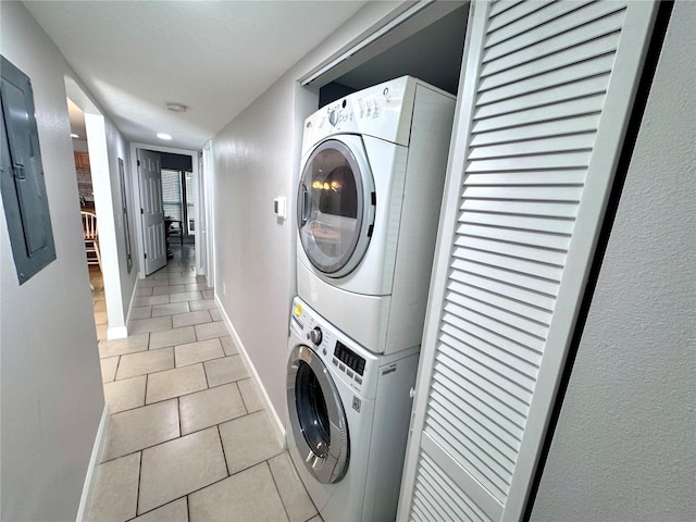 washroom featuring light tile patterned floors, baseboards, and stacked washer / dryer