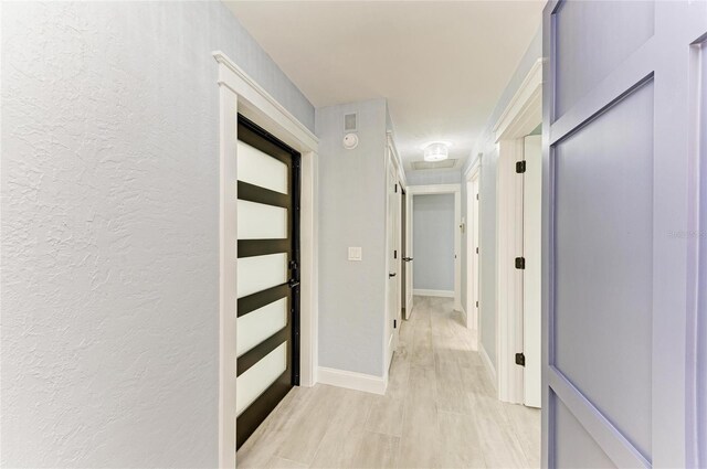 corridor with baseboards and a textured wall