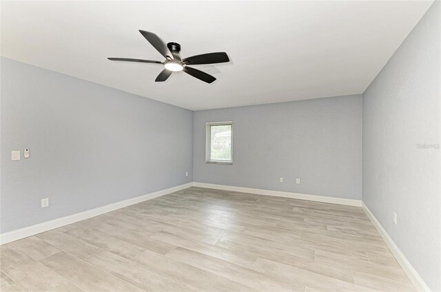 empty room featuring ceiling fan, baseboards, and light wood finished floors