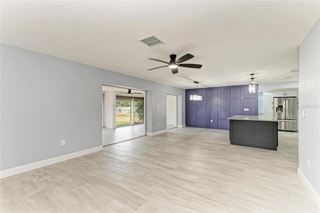 unfurnished living room with visible vents, baseboards, ceiling fan, and light wood-type flooring