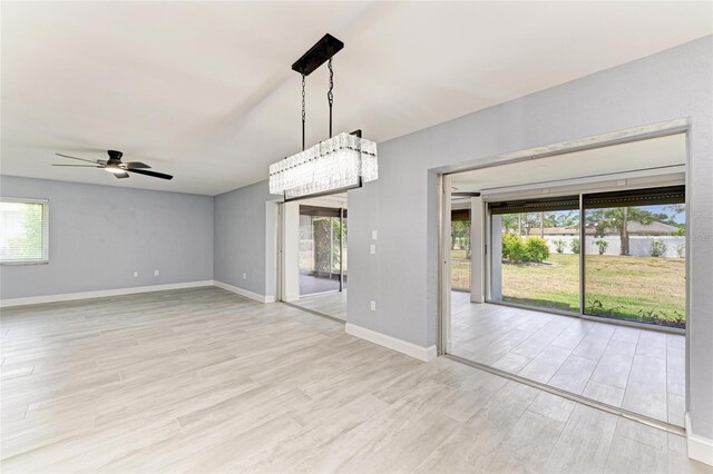 unfurnished room featuring a healthy amount of sunlight, ceiling fan, and light wood-style flooring