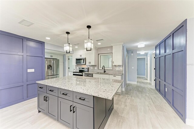 kitchen featuring a sink, appliances with stainless steel finishes, light stone counters, and visible vents