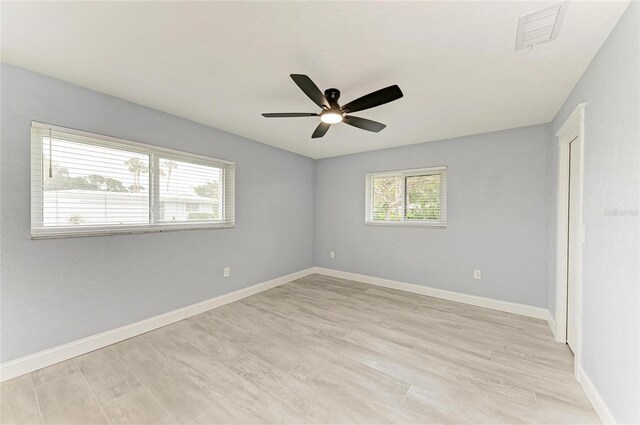 empty room featuring visible vents, a ceiling fan, light wood-style flooring, and baseboards