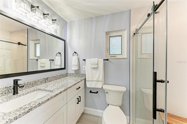 full bath featuring vanity, baseboards, a stall shower, and toilet