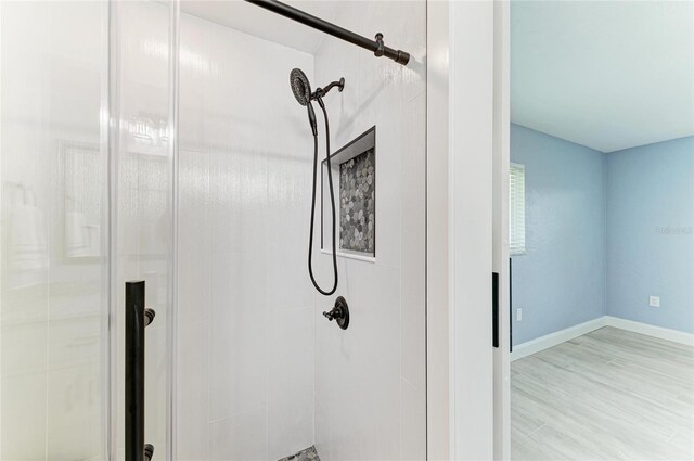 room details with baseboards, a shower stall, and wood finished floors