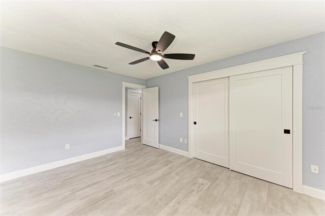 unfurnished bedroom with visible vents, a closet, baseboards, ceiling fan, and light wood-style flooring