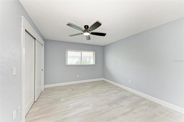 unfurnished bedroom featuring a ceiling fan, baseboards, light wood-style flooring, and a closet